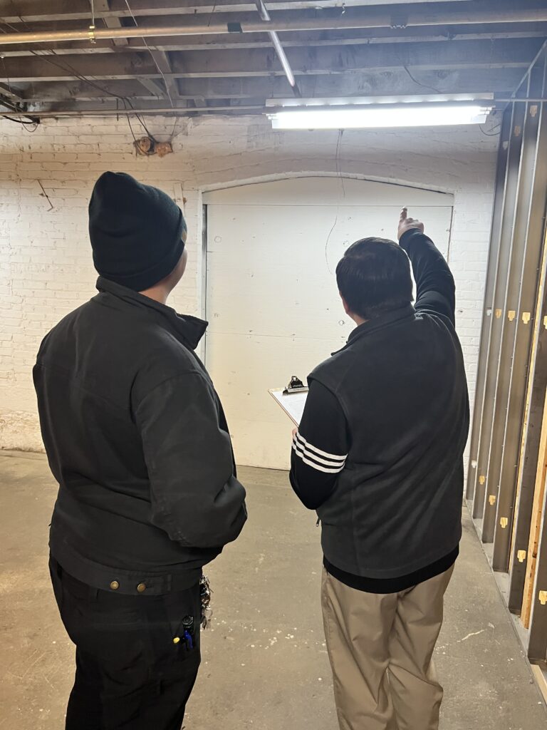 Two people inspecting a basement wall